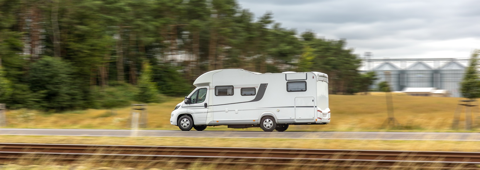 A white camper van driving on the road, motion blur effect highlights the sense of speed and freedom of travel.